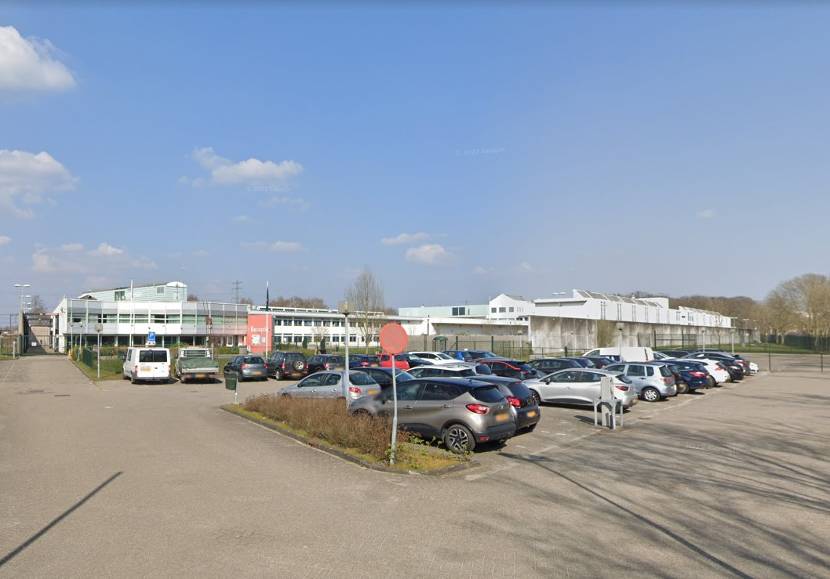 Het gebouw van Handhaving- en Toezichtslocatie Hoogeveen vanaf de straat gezien. Op de voorgrond een parkeerplaats.