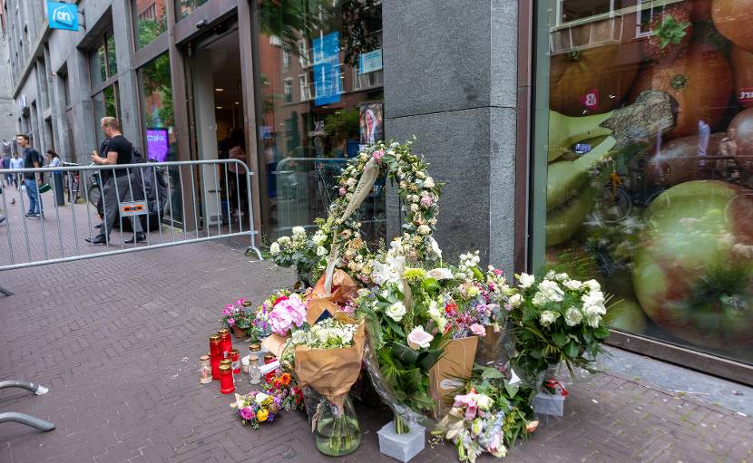 Bloemen en rouwkransen naast de ingang van een Albert Heijn supermarkt filiaal.